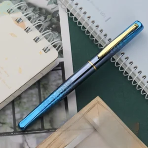 Pluma estilográfica azul iridiscente con clip dorado sobre un cuaderno de espiral